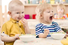 Drei Kinder im Kitaalter sitzen am Tisch und essen Obst.