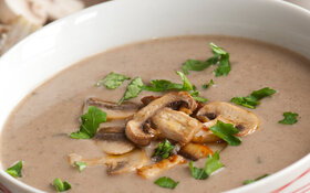Pilzsuppe mit Champignons in einer weißen Suppenschüssel serviert.