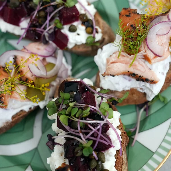 Lachs-Crostini und Rote-Bete-Crostini nach einem Rezept von Felicitas Then, angerichtet auf einem grün-weißem Teller, garniert mit Dill und Microgreens.
