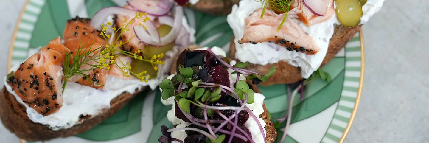 Lachs-Crostini und Rote-Bete-Crostini nach einem Rezept von Felicitas Then, angerichtet auf einem grün-weißem Teller, garniert mit Dill und Microgreens.