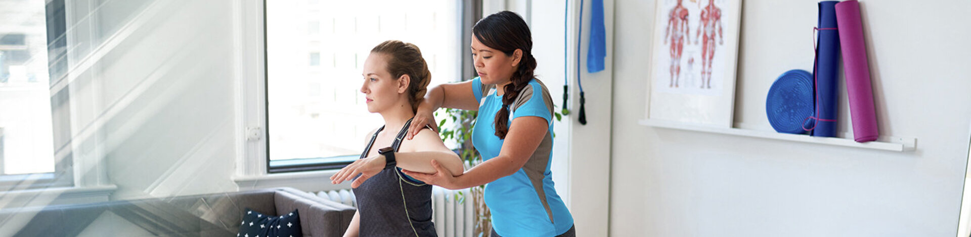 Chinesische Frau Physiotherapie Professionelle gibt eine Behandlung zu einem attraktiven blonden Kunden in einem hellen medizinischen Büro – Stockfoto