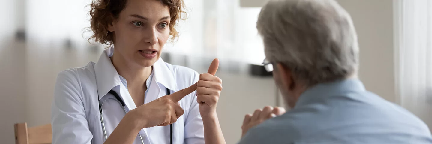 Eine junge Ärztin spricht mit einem Patienten über Blut im Stuhl.