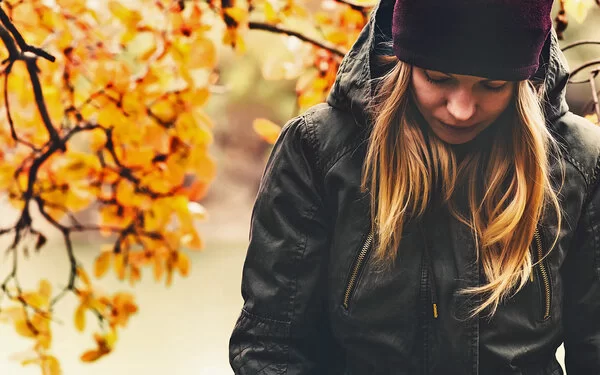 Eine Frau, die unter Herbstblues leidet, geht im Wald spazieren.