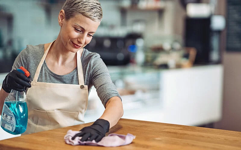 Eine Frau putzt mit Putzhandschuhen, um einer chronischen Paronychie vorzubeugen.