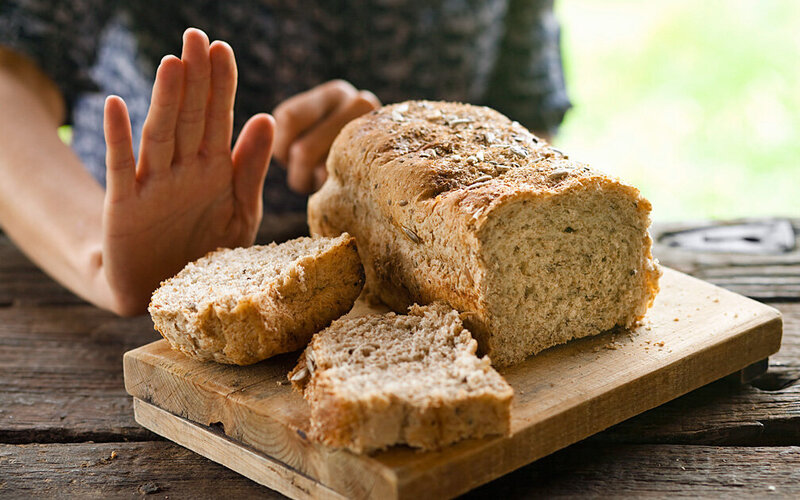 Eine Hand zeigt eine Abwehrgeste vor einem aufgeschnittenen Laib Brot.