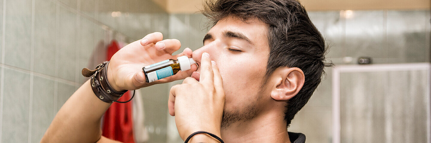 Junger Mann benutzt Nasenspray, weil er unter einer Nasenspraysucht leidet.