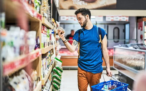 Kunde im Supermarkt checkt den Nutri-Score vom Produkt.