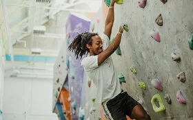 Ein junger Mann beim Bouldern in einer Boulderhalle.