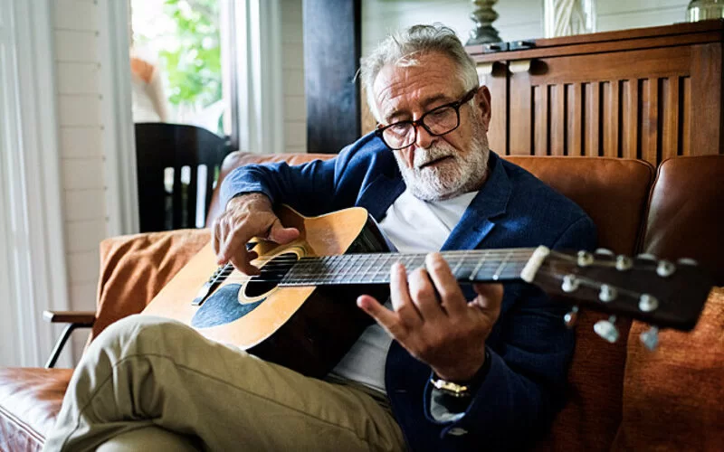 Ein älterer Mann lernt Gitarre zu spielen.