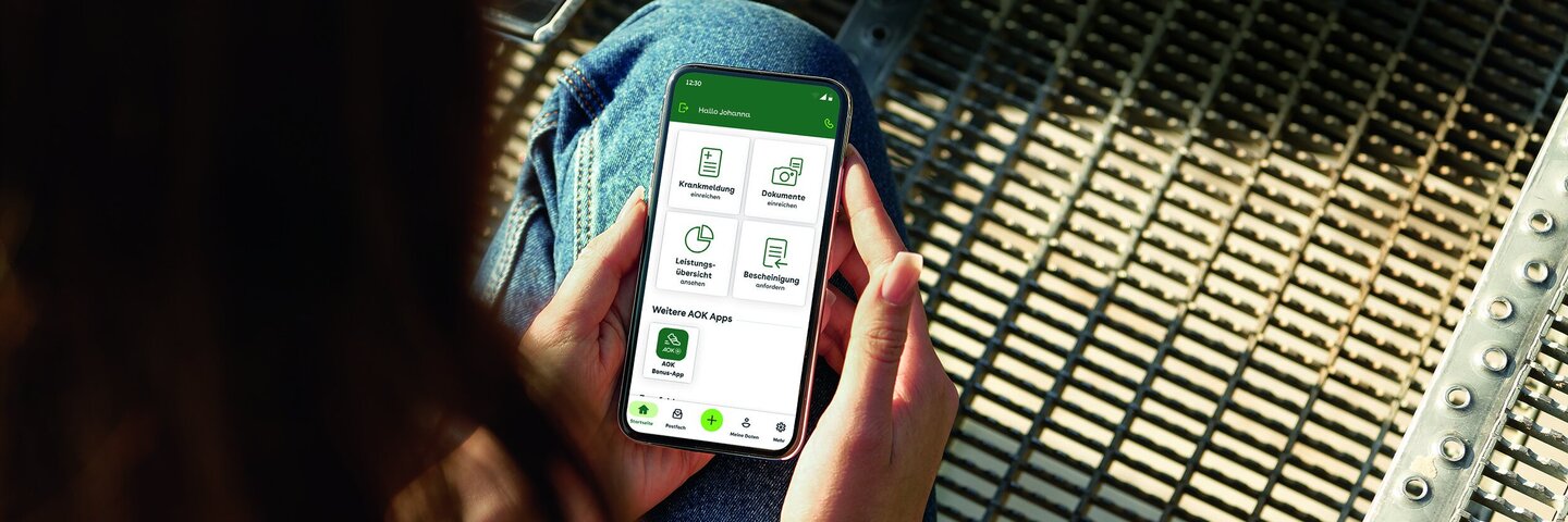 Eine junge Frau blickt auf ihr Smartphone. Mit dem Portal “Meine AOK” hat sie alle Informationen griffbereit.