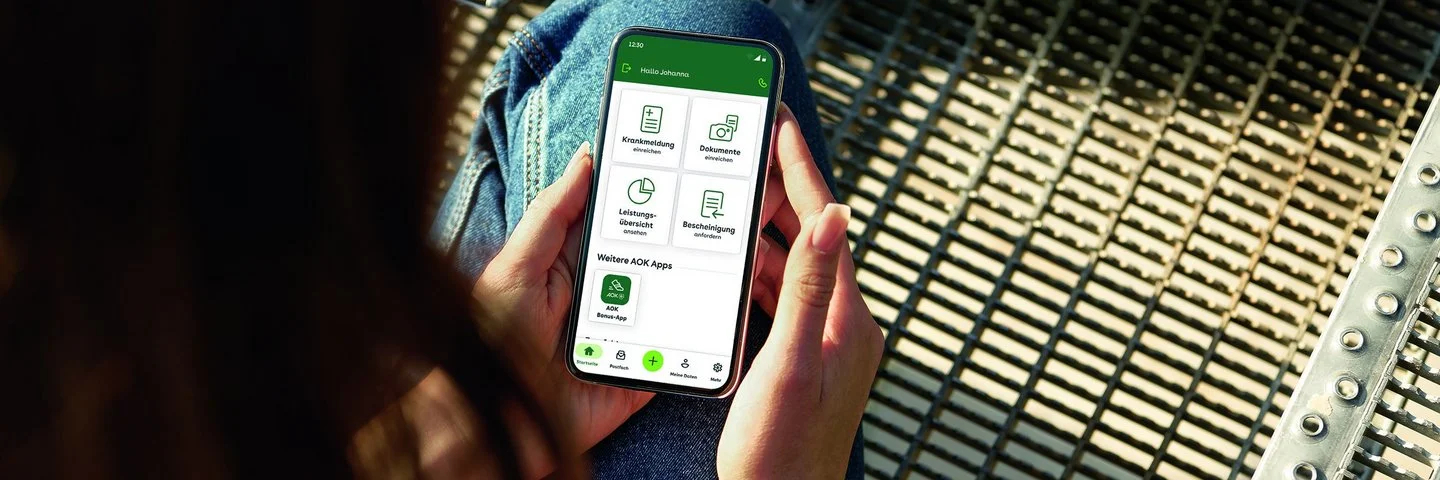 Eine junge Frau blickt auf ihr Smartphone. Mit dem Portal “Meine AOK” hat sie alle Informationen griffbereit.