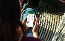 Eine junge Frau blickt auf ihr Smartphone. Mit dem Portal “Meine AOK” hat sie alle Informationen griffbereit.
