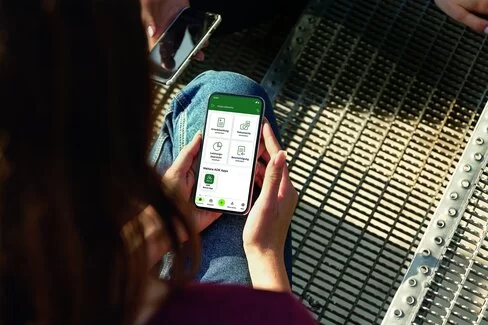 Eine junge Frau blickt auf ihr Smartphone. Mit dem Portal “Meine AOK” hat sie alle Informationen griffbereit.
