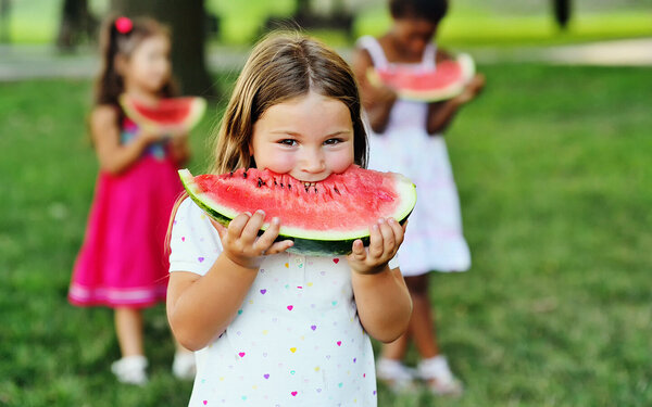 Ein Mädchen isst Wassermelone im Park mit ihren Freundinnen.
