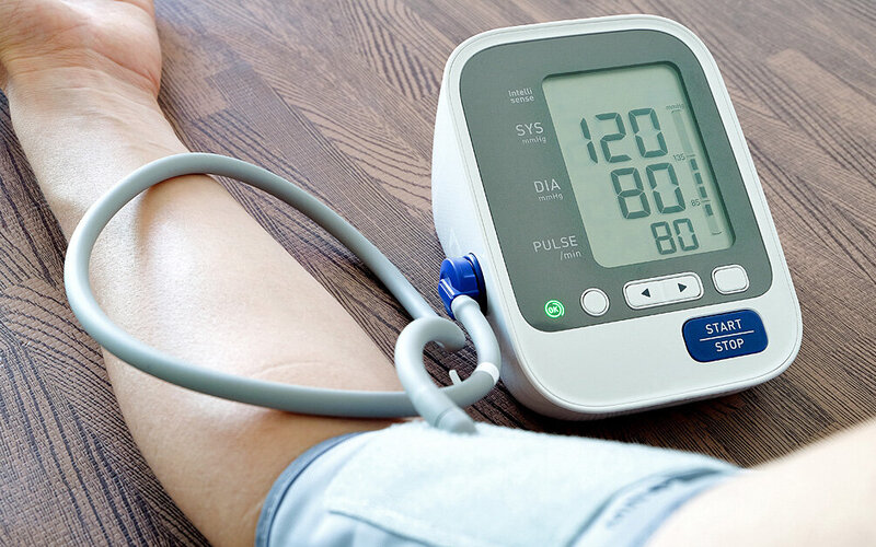 Mann misst seinen Blutdruck mit Hilfe eines Blutdruckmessgerätes.