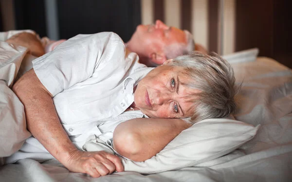 Eine Frau mit Diabetes liegt traurig neben ihrem Mann im Bett.