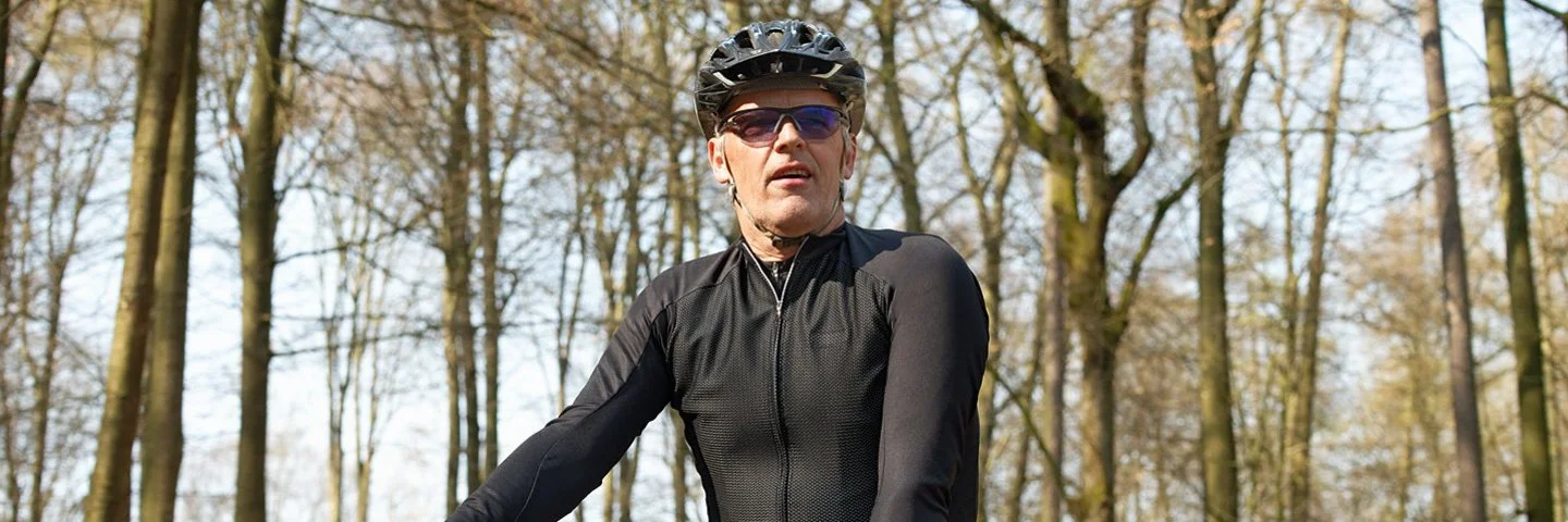 Ein Mann fährt mit dem Fahrrad durch den Wald. Durch seine gesunde Lebensweise profitiert er vom Bonus- und Prämienprogramm der AOK.