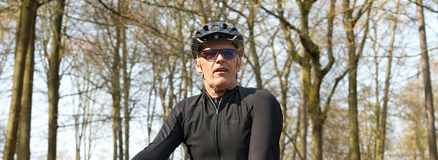 Ein Mann fährt mit dem Fahrrad durch den Wald. Durch seine gesunde Lebensweise profitiert er vom Bonus- und Prämienprogramm der AOK.