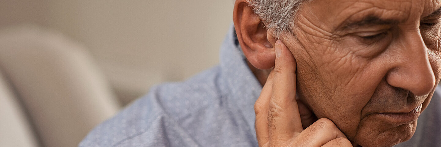 Ein älterer Mann hat Druck auf den Ohren beim Fliegen.