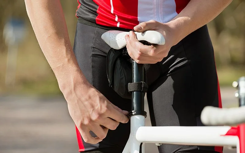 Ein Mann stellt die Sattelhöhe am Fahrrad ein.