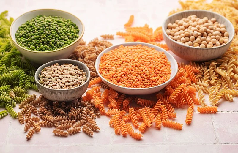 Pasta aus Linsen, Erbsen und Kichererbsen neben den jeweiligen Hülsenfrüchten in Schalen.