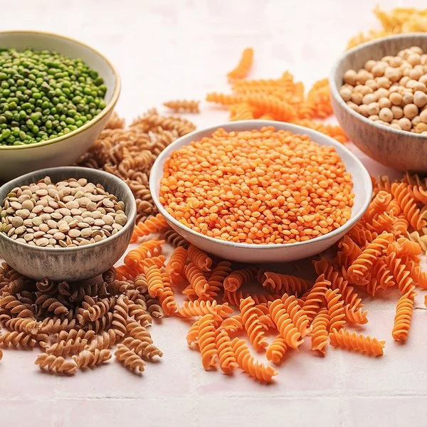 Pasta aus Linsen, Erbsen und Kichererbsen neben den jeweiligen Hülsenfrüchten in Schalen.