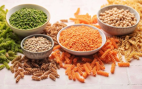 Pasta aus Linsen, Erbsen und Kichererbsen neben den jeweiligen Hülsenfrüchten in Schalen.