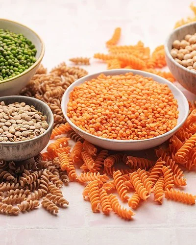 Pasta aus Linsen, Erbsen und Kichererbsen neben den jeweiligen Hülsenfrüchten in Schalen.