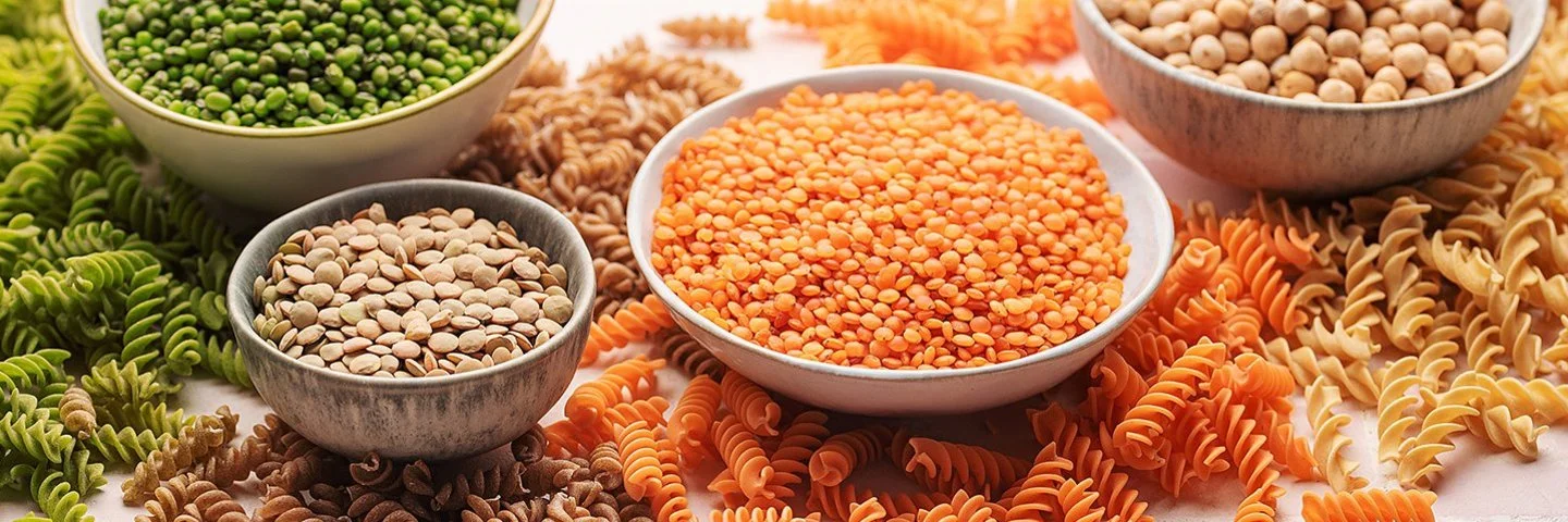 Pasta aus Linsen, Erbsen und Kichererbsen neben den jeweiligen Hülsenfrüchten in Schalen.