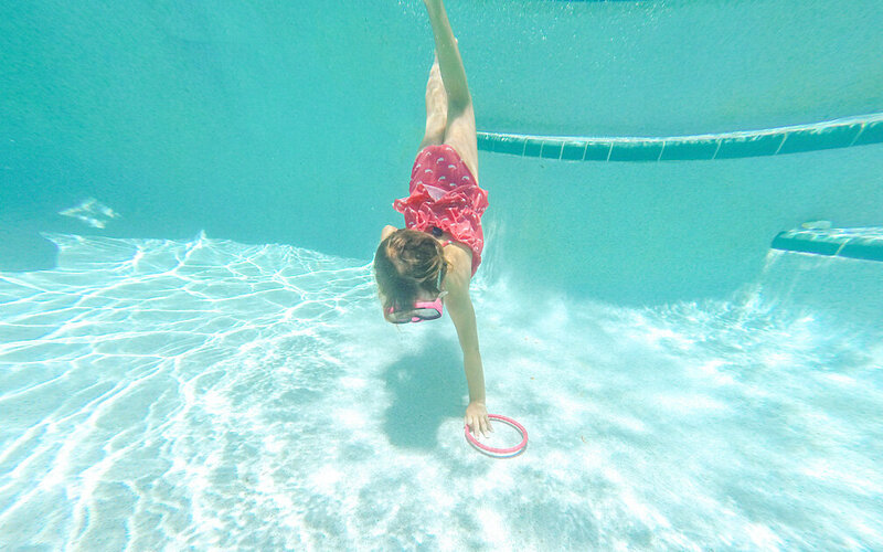 Ein Mädchen taucht nach einem Tauchring im Rahmen einer Schwimmabzeichen-Prüfung.