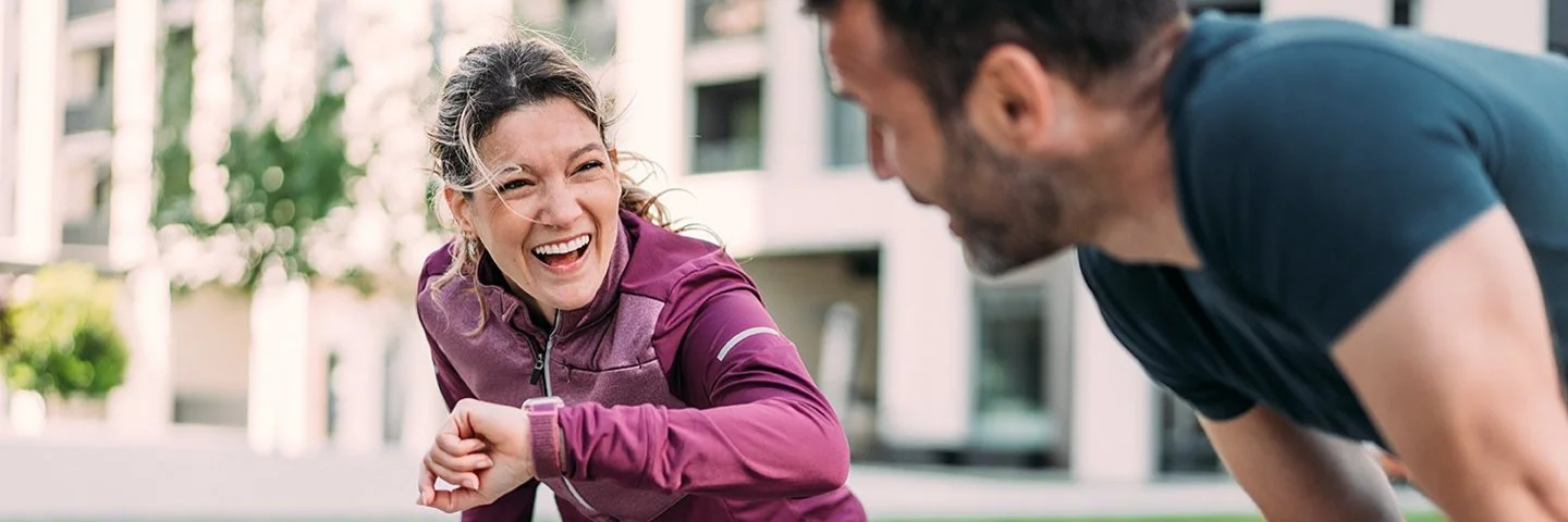 Eine Frau und ein Mann freuen sich über ihr erfolgreiches Lauftraining in der Stadt.