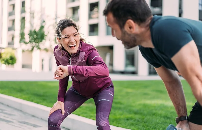 Eine Frau und ein Mann freuen sich über ihr erfolgreiches Lauftraining in der Stadt.