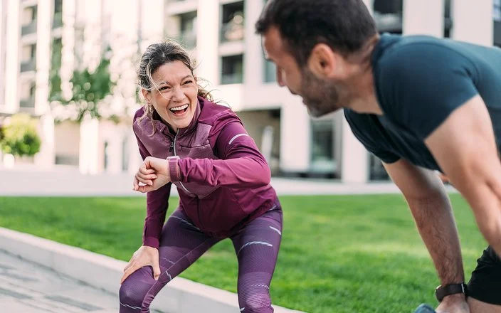 Eine Frau und ein Mann freuen sich über ihr erfolgreiches Lauftraining in der Stadt.