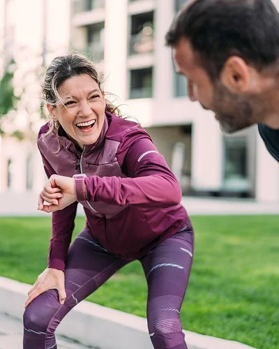 Eine Frau und ein Mann freuen sich über ihr erfolgreiches Lauftraining in der Stadt.