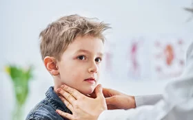Eine Kinderärztin tastet den Hals eines kleinen Jungen nach Anzeichen von Mumps ab.