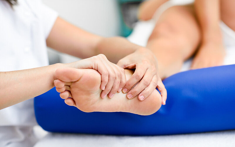 Physiotherapeutin massiert Patientin ihren Senkfuß.