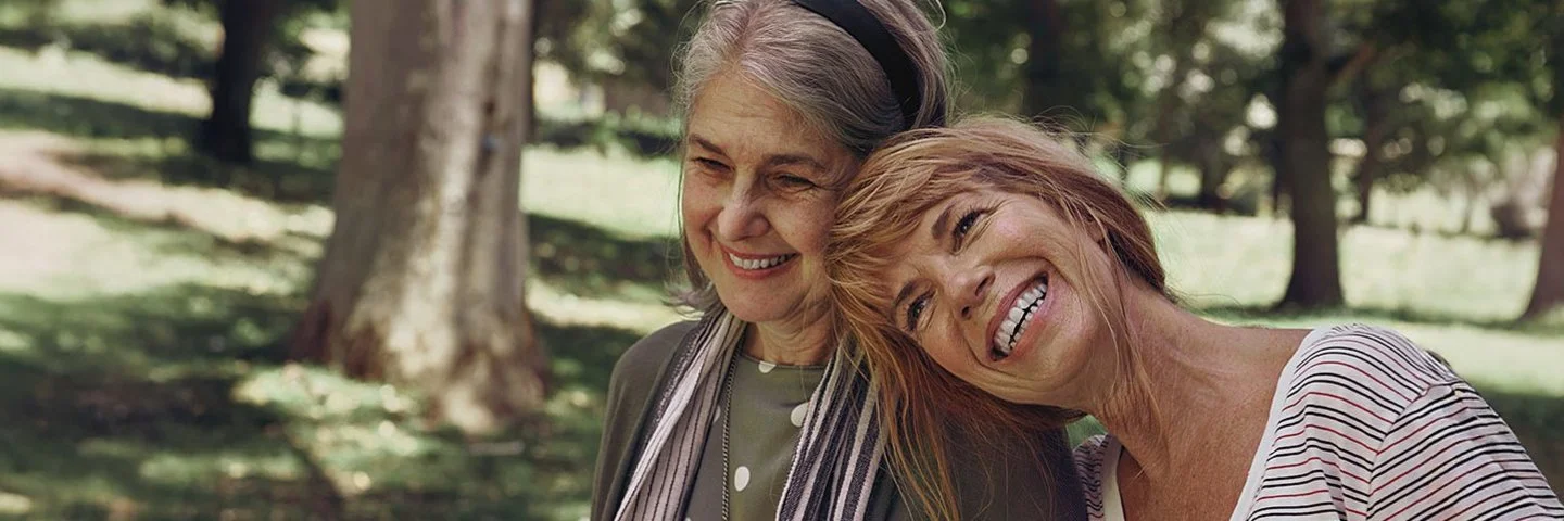 Zwei Seniorinnen gehen gemeinsam im Park spazieren.