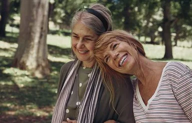 Zwei Seniorinnen gehen gemeinsam im Park spazieren.