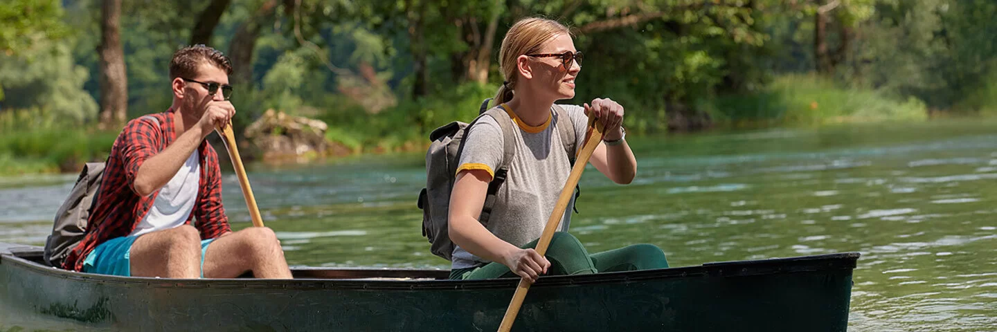 Ein junges Paar rudert in einem Kanu auf einem Fluss.
