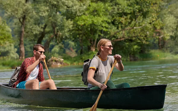 Ein junges Paar rudert in einem Kanu auf einem Fluss.