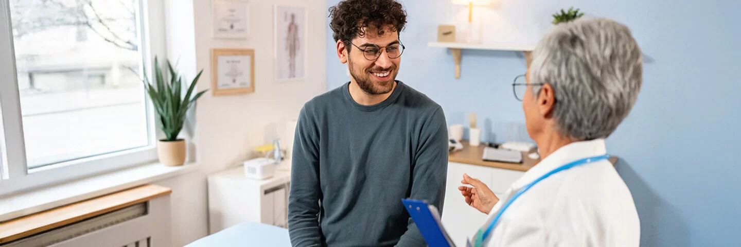 Männlicher Patient, der bei der Ordination eine jährliche medizinische Untersuchung bei einer älteren Ärztin erhält