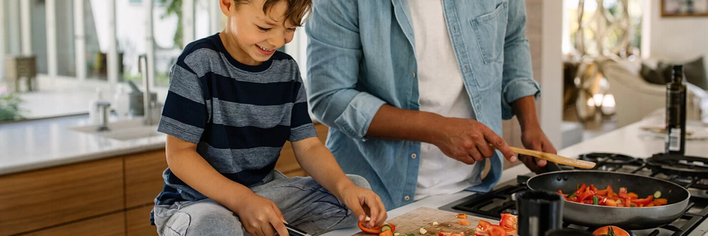 Vater und Sohn kochen zusammen in der Küche mit gesunden Lebensmitteln.