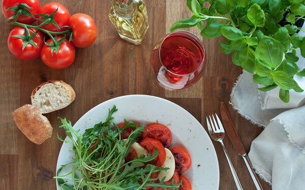 Gedeckter Tisch mit den histaminreichen Lebensmitteln Tomaten, Weißbrot und Rotwein.