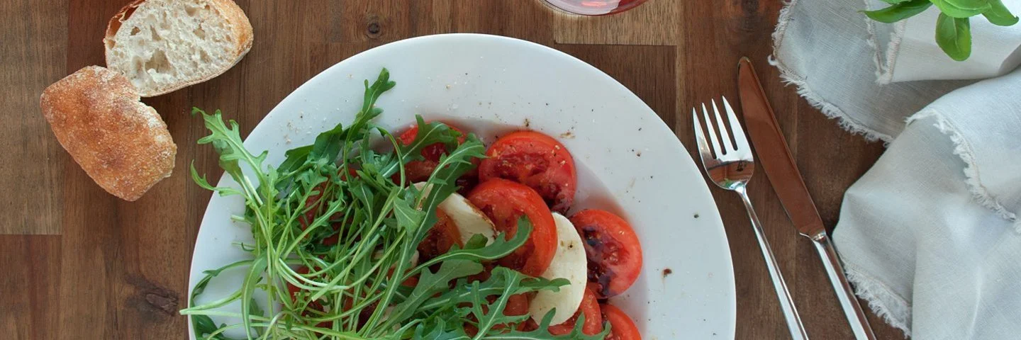 Gedeckter Tisch mit den histaminreichen Lebensmitteln Tomaten, Weißbrot und Rotwein.
