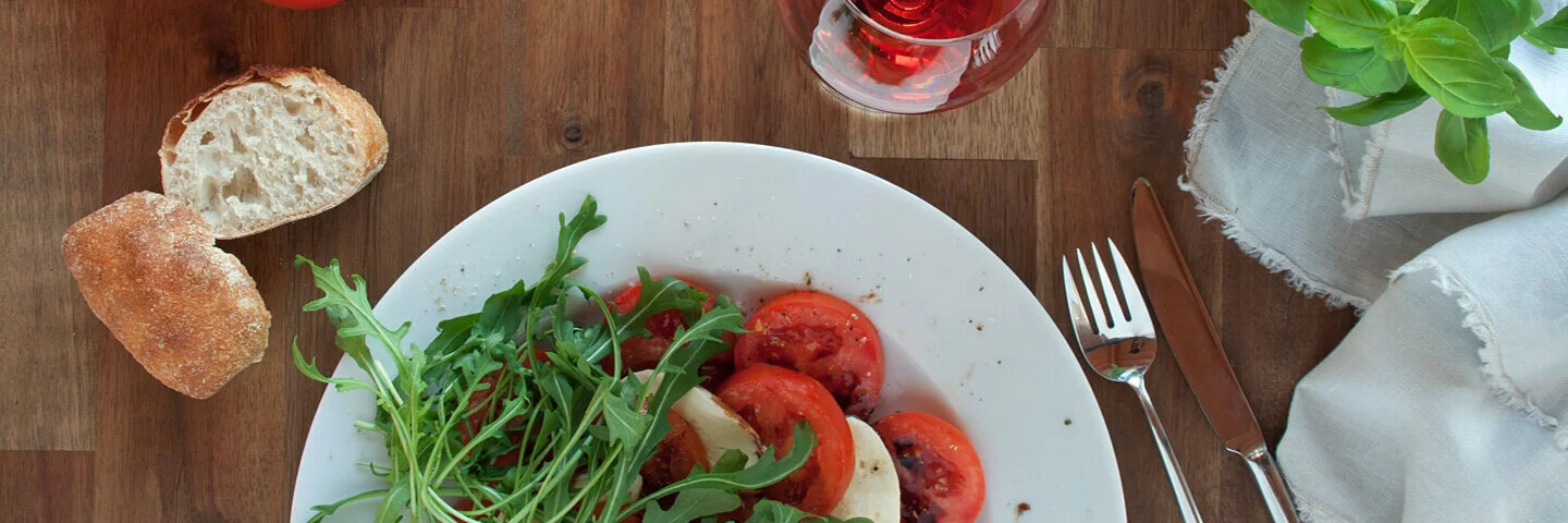 Gedeckter Tisch mit den histaminreichen Lebensmitteln Tomaten, Weißbrot und Rotwein.