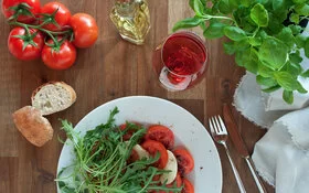 Gedeckter Tisch mit den histaminreichen Lebensmitteln Tomaten, Weißbrot und Rotwein.