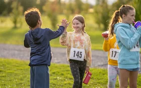 Kinder bei der Leichtathletik geben sich ein High Five.