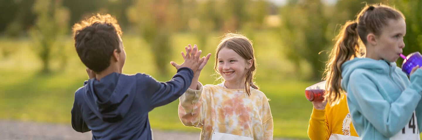 Kinder bei der Leichtathletik geben sich ein High Five.