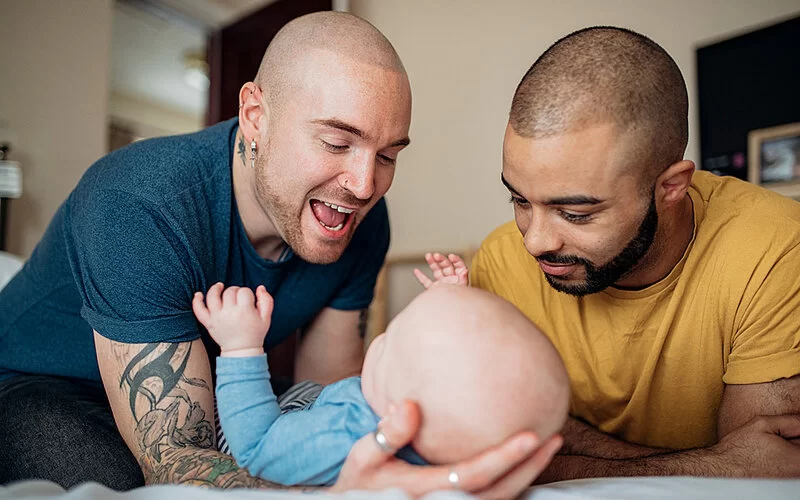 Zwei Väter kümmern sich um ihr Neugeborenes, um das Bonding zu stärken.