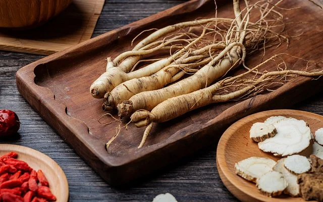 Vier Ginsengwurzeln liegen nebeneinander auf einem hölzernen Tablett.